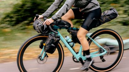 Jack Wolfskin bike packing luggage shown mounted on a blue bike ridden by a male rider with greenery in the background